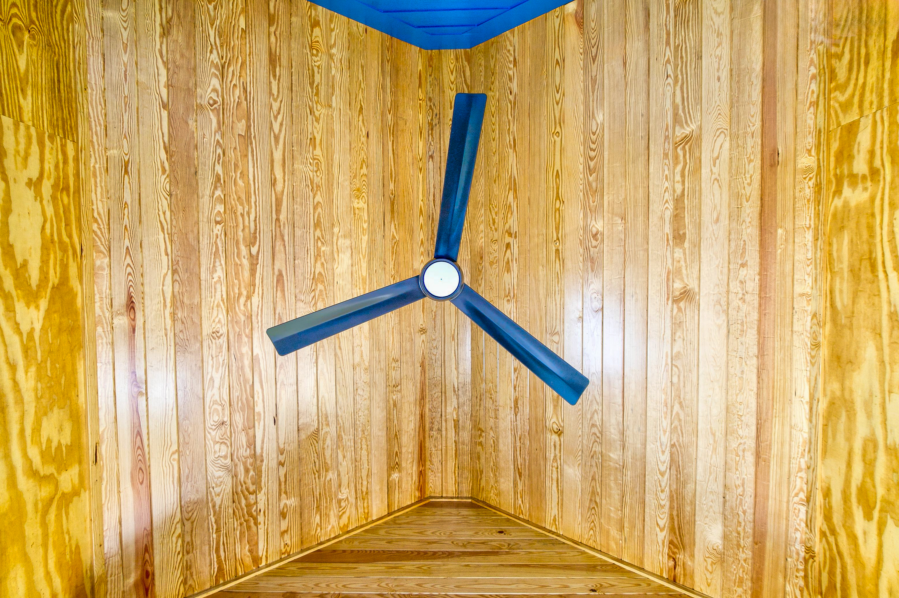 Direct view of the wooden ceiling of the screened in porch from underneath the ceiling fan. 
