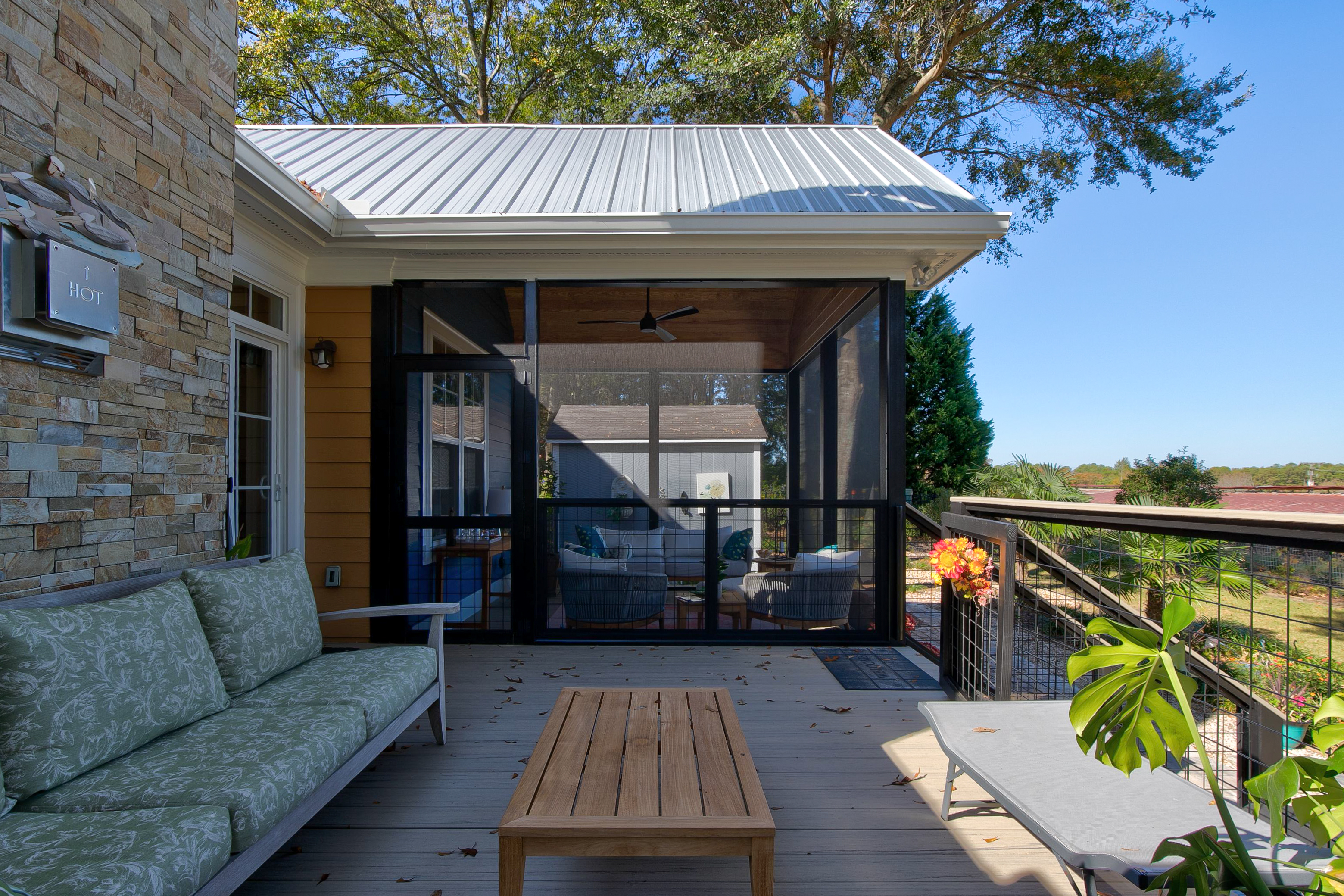 View of screened section of a screened back porch from the unscreened section of the back porch. 