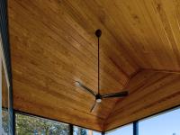 Wooden ceiling of a screened back porch with a ceiling fan.