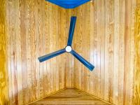 Direct view of the wooden ceiling of the screened in porch from underneath the ceiling fan.