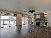 Custom Rafter B living room featuring stone fireplace and large open sliding glass doors in a lakeside home