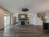 Custom Rafter B living room featuring stone fireplace and large open sliding glass doors in a lakeside home