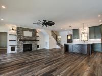 Custom Rafter B living room featuring stone fireplace and large open sliding glass doors in a lakeside home