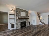 Custom Rafter B living room featuring stone fireplace and large open sliding glass doors in a lakeside home