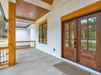 Front porch of white craftsman style home with wood accents