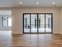 Room with white walls and wooden floors with glass doors to back porch - Rafter B Construction custom home