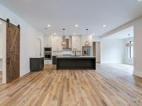 Room with white walls and wooden floors and open concept kitchen - Rafter B Construction custom home