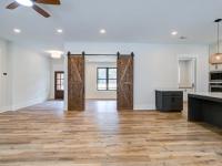 Room with white walls and wooden floors and open concept kitchen - Rafter B Construction custom home