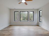 Room with wood floors, white walls and large windows and ceiling fan