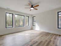 Room with wood floors, white walls and large windows and ceiling fan