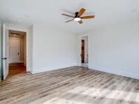 Room with wood floors, white walls and large windows and ceiling fan