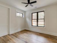 Room with wood floors, white walls and large windows and ceiling fan