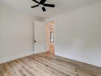 Room with wood floors, white walls and large windows and ceiling fan