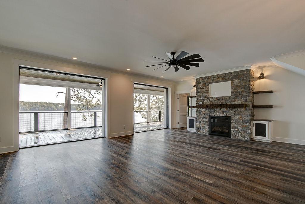 Custom Rafter B living room featuring stone fireplace and large open sliding glass doors in a lakeside home