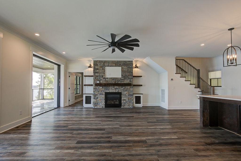 Custom Rafter B living room featuring stone fireplace and large open sliding glass doors in a lakeside home