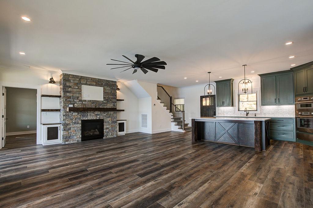 Custom Rafter B living room featuring stone fireplace and large open sliding glass doors in a lakeside home
