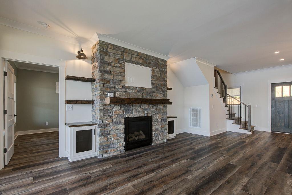Custom Rafter B living room featuring stone fireplace and large open sliding glass doors in a lakeside home