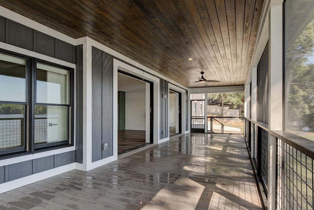 Screened porch on rear of custom home featuring wooden floors and ceiling and large sliding glass doors