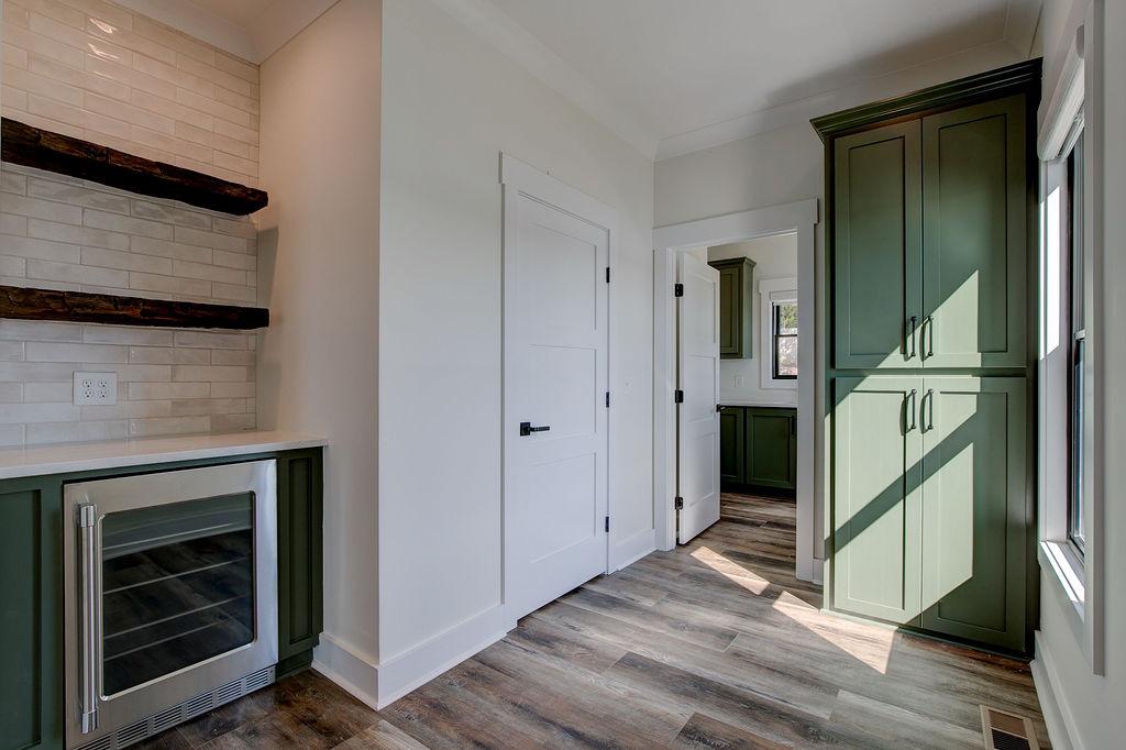Interior hallway with built-in cabinetry and wooden floors and beverage cooler