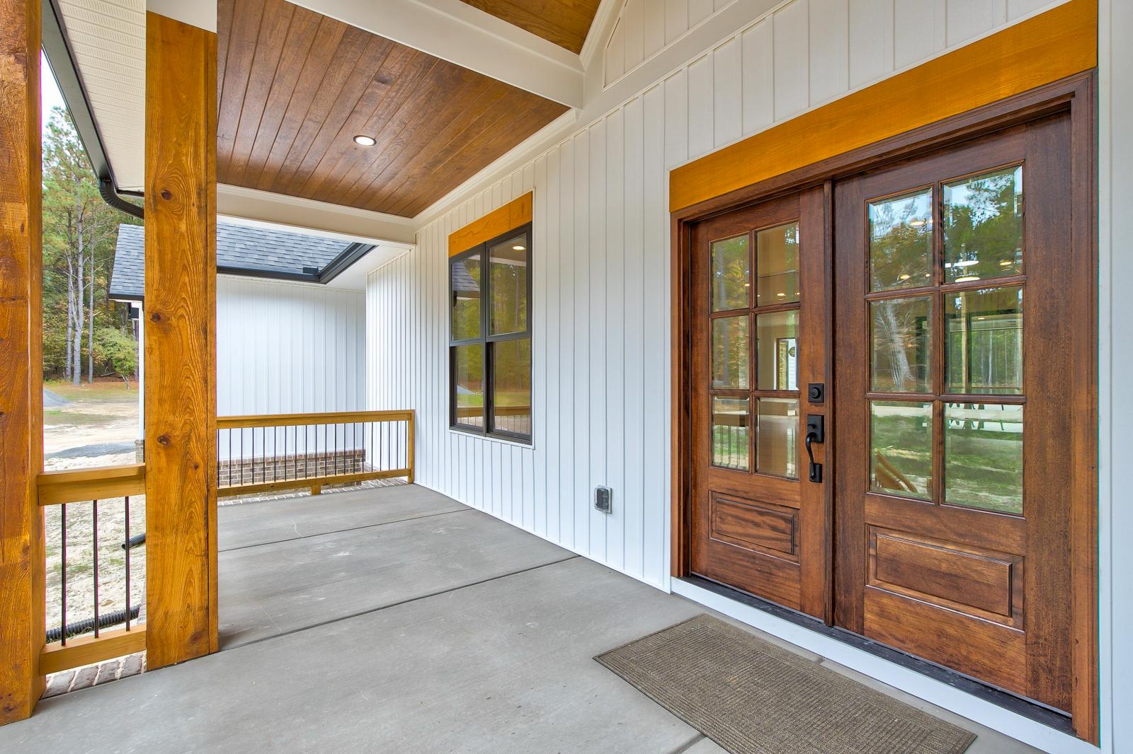 Front porch of white craftsman style home with wood accents