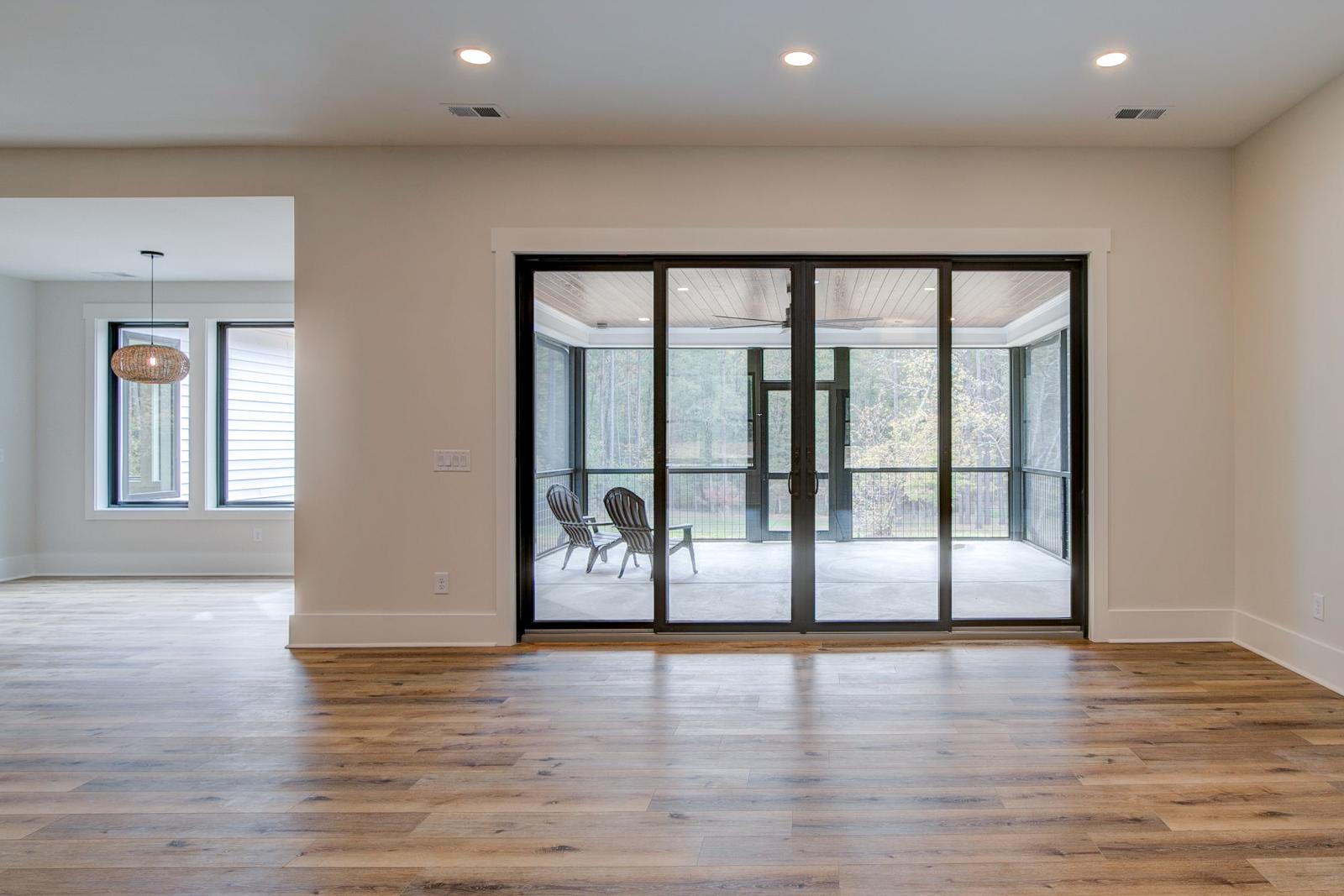 Room with white walls and wooden floors with glass doors to back porch - Rafter B Construction custom home