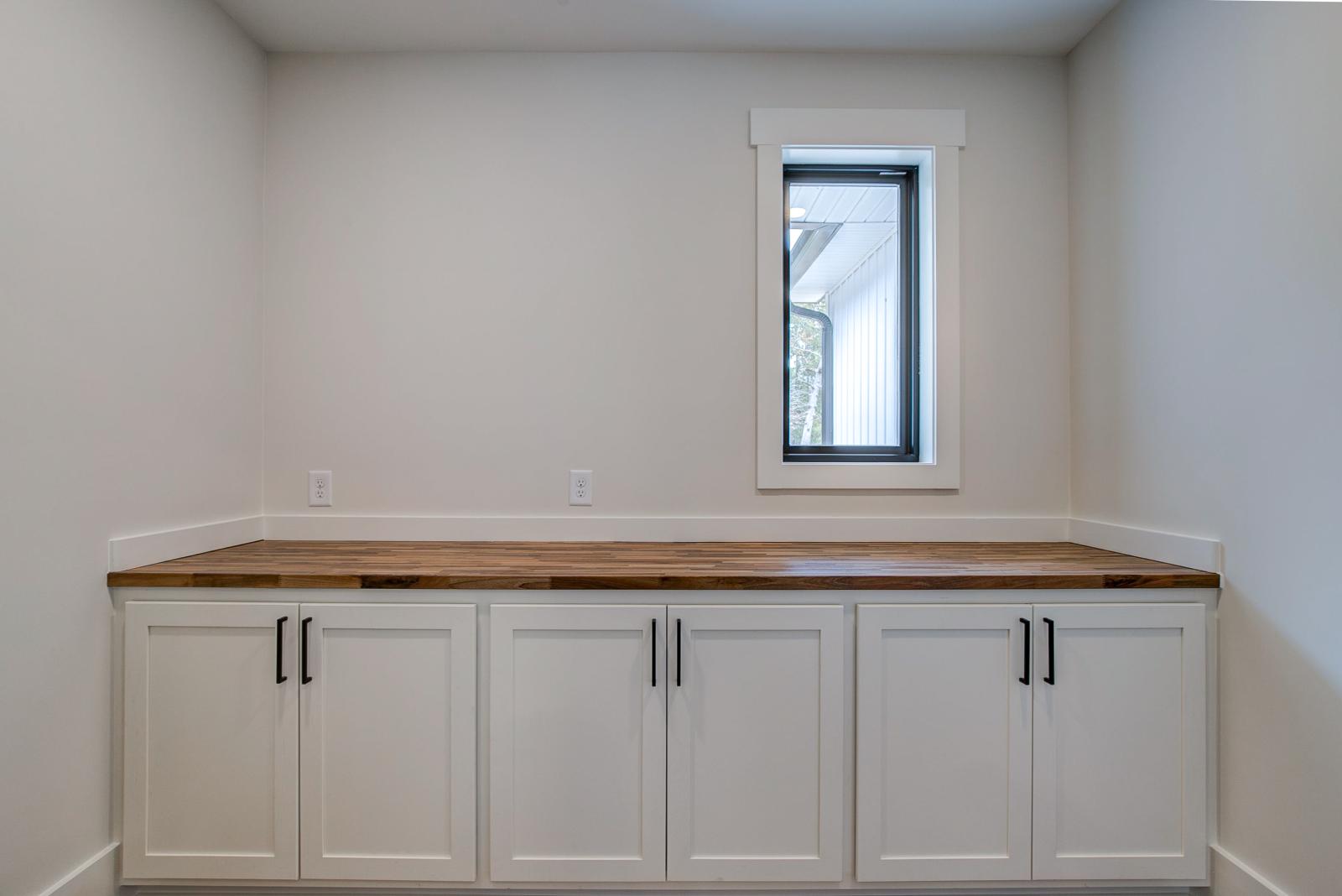 Butler's Pantry off of the main kitchen with white cabinets and prep space