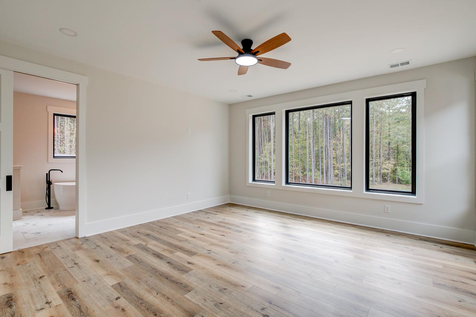 Room with wood floors, white walls and large windows and ceiling fan