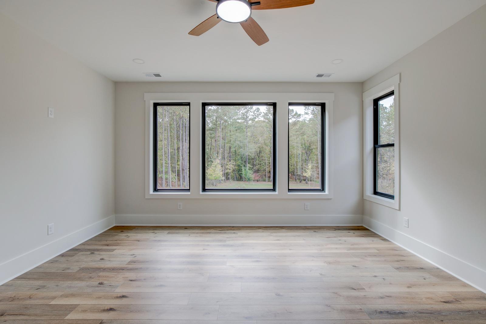 Room with wood floors, white walls and large windows and ceiling fan
