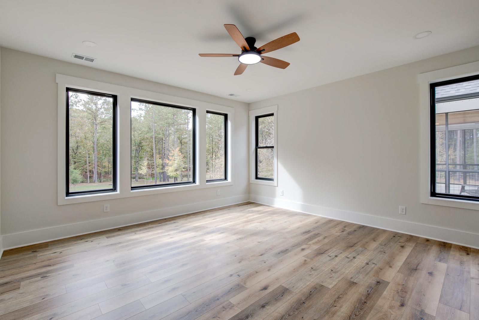 Room with wood floors, white walls and large windows and ceiling fan
