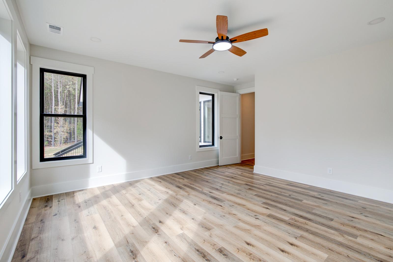 Room with wood floors, white walls and large windows and ceiling fan
