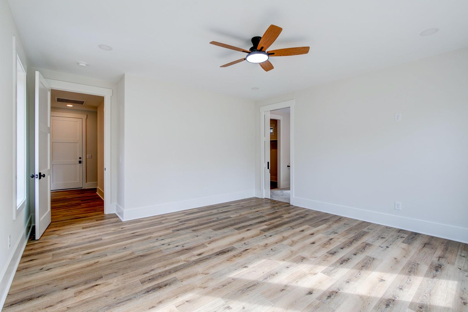 Room with wood floors, white walls and large windows and ceiling fan