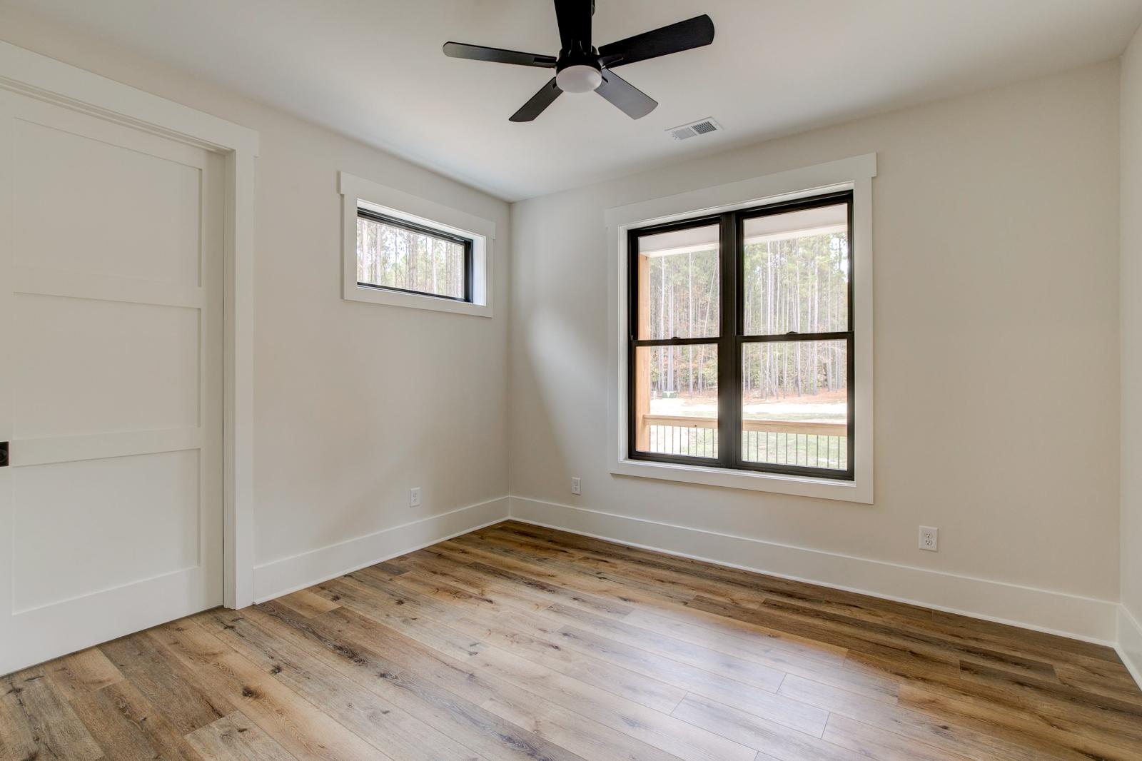Room with wood floors, white walls and large windows and ceiling fan