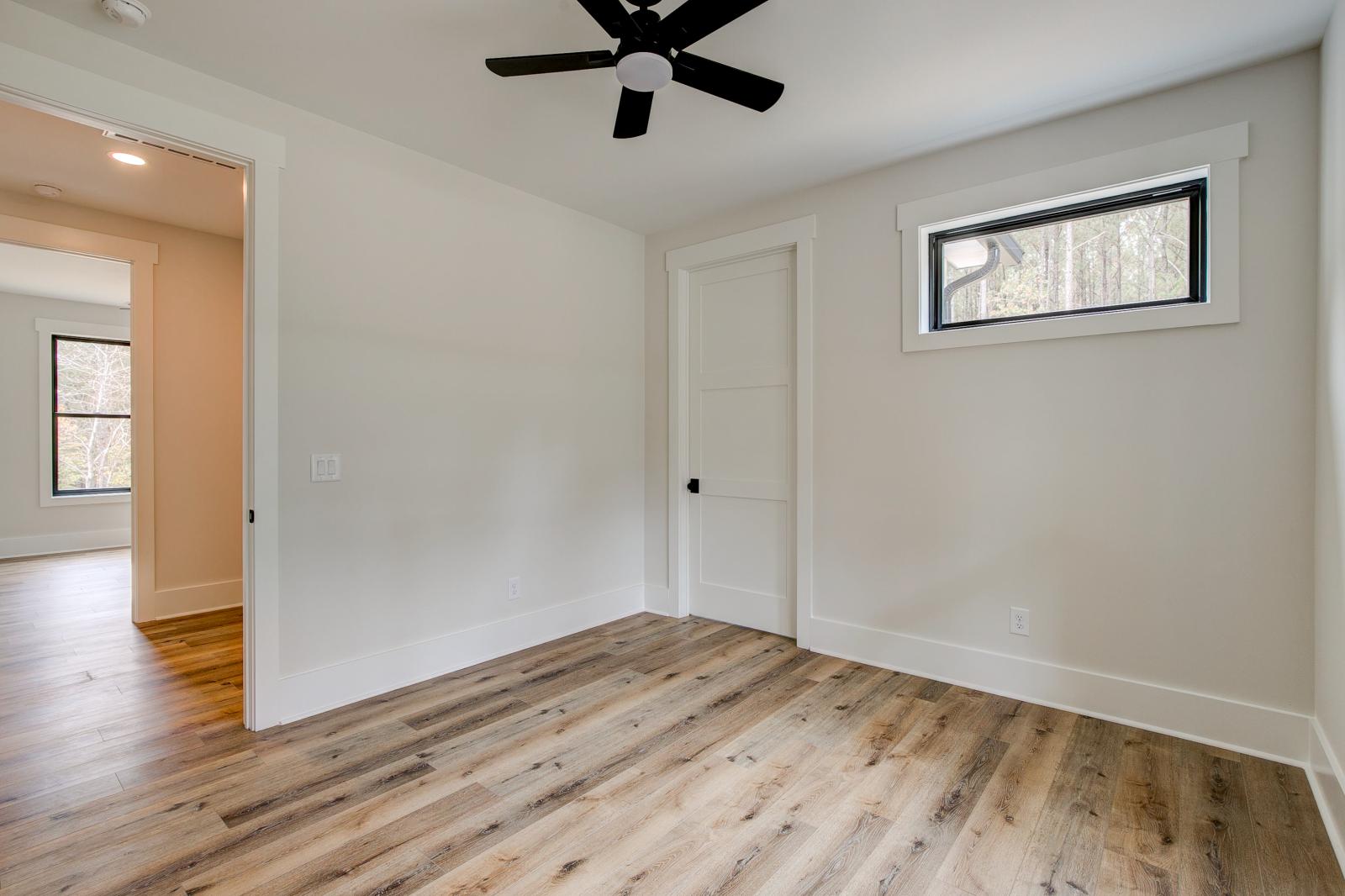 Room with wood floors, white walls and large windows and ceiling fan