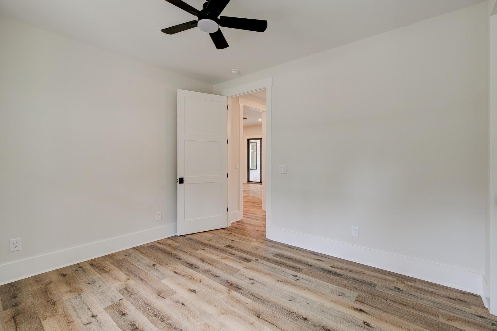 Room with wood floors, white walls and large windows and ceiling fan