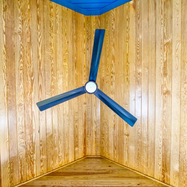 Direct view of the wooden ceiling of the screened in porch from underneath the ceiling fan.